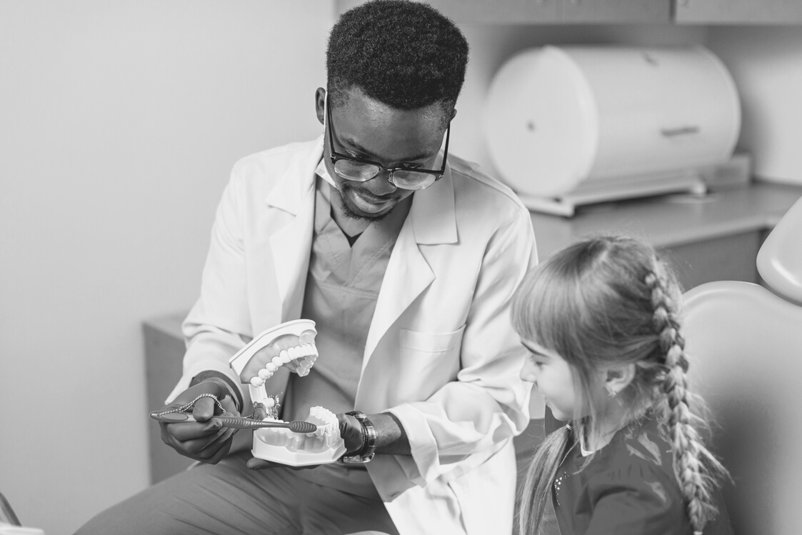 Young beautiful girl in dental office. African children's dentist examines teeth to a child.
